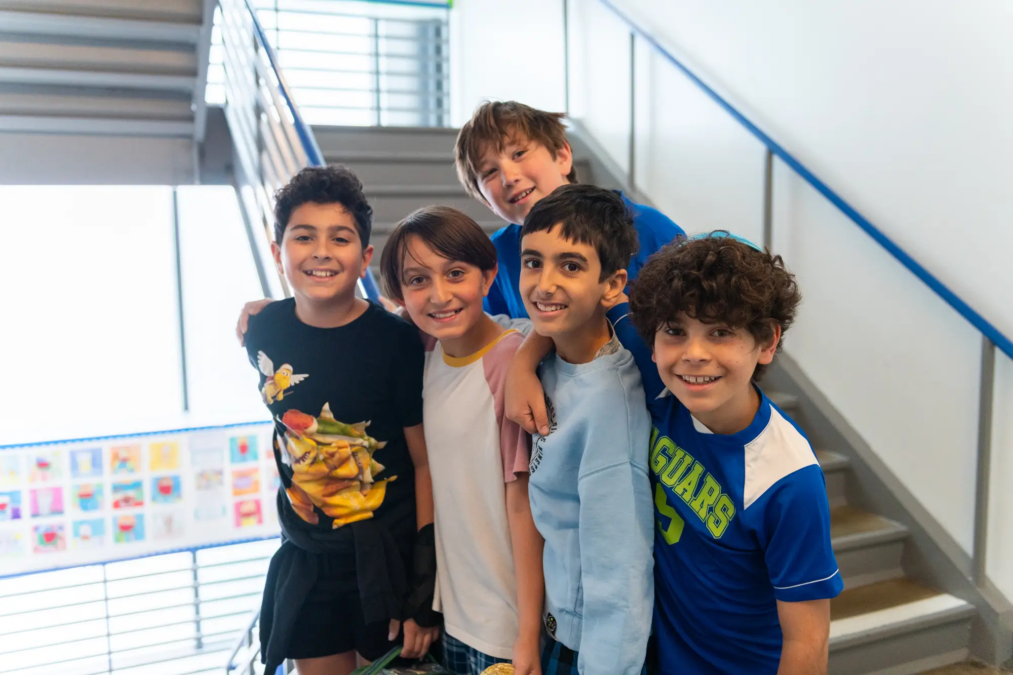 Five boys posing for the camera in a school stairway.